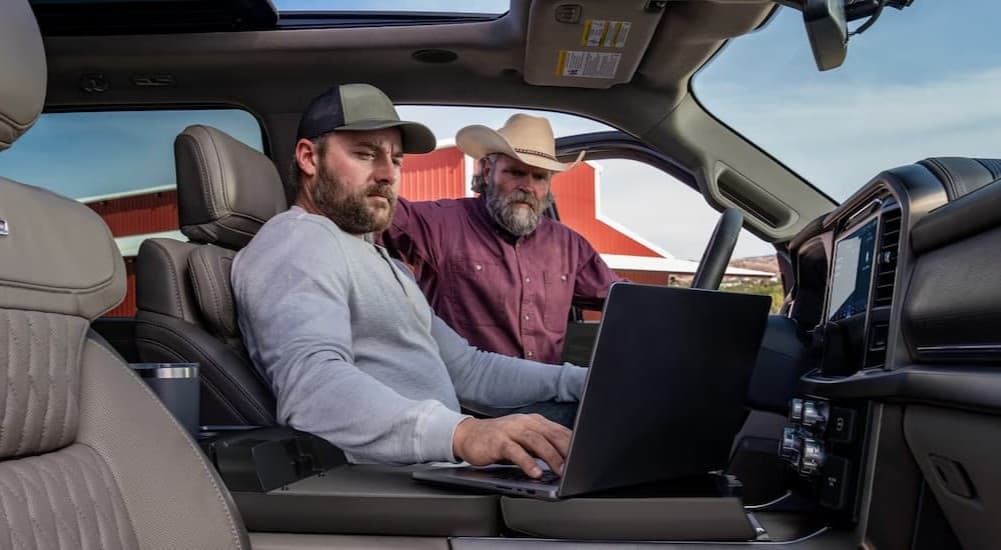 Two people using a laptop in a 2026 Ford F-150.