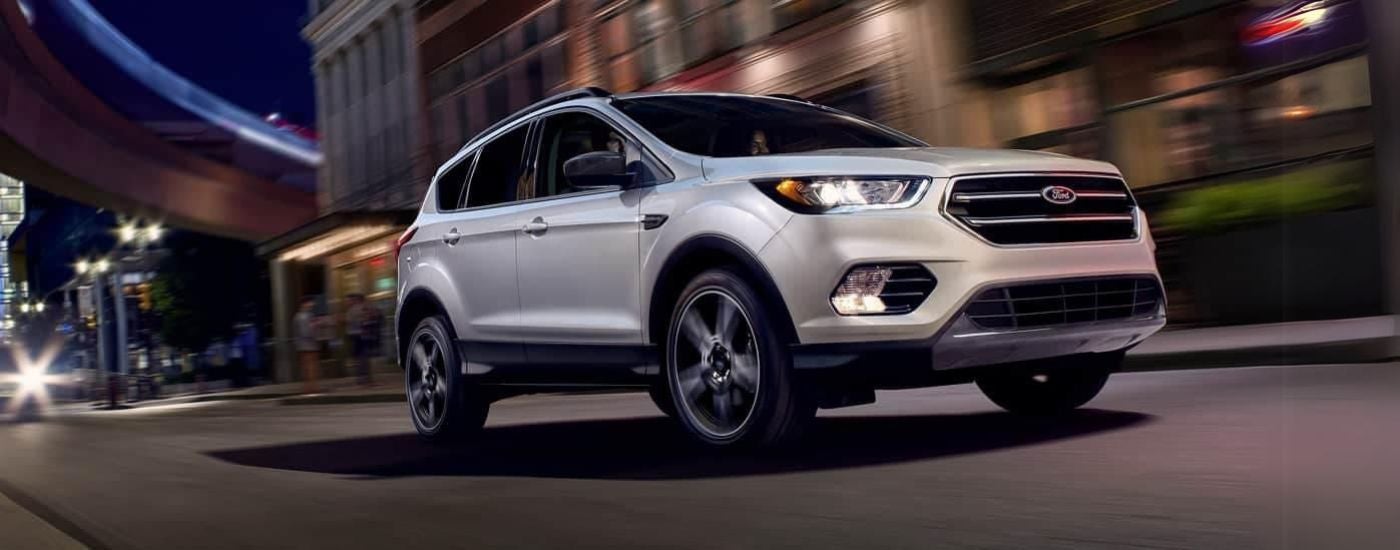 White 2019 Ford Escape driving down an open road in a city.