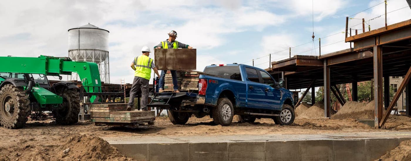 Rear of a blue 2020 Ford F-250 parked off-road at a construction zone.
