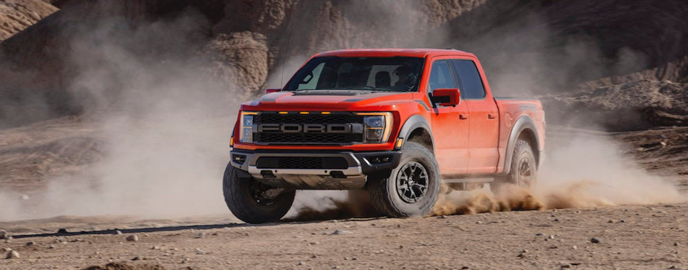 Orange 2021 Ford F-150 Raptor drifting off-road