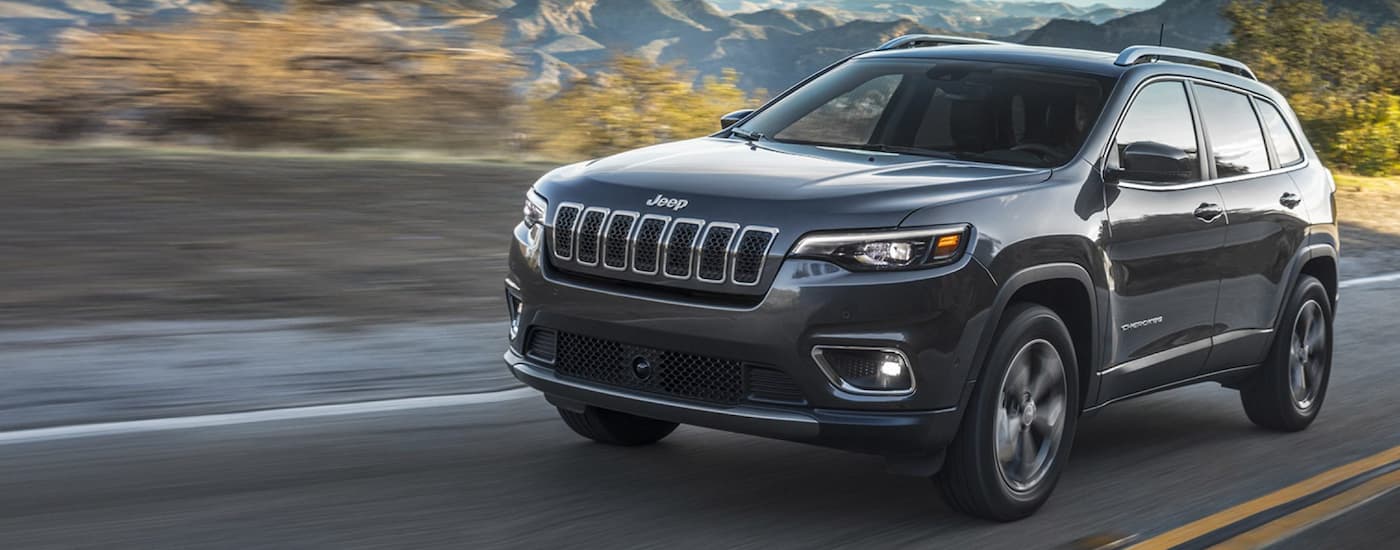 Black 2021 Jeep Cherokee driving down a road.