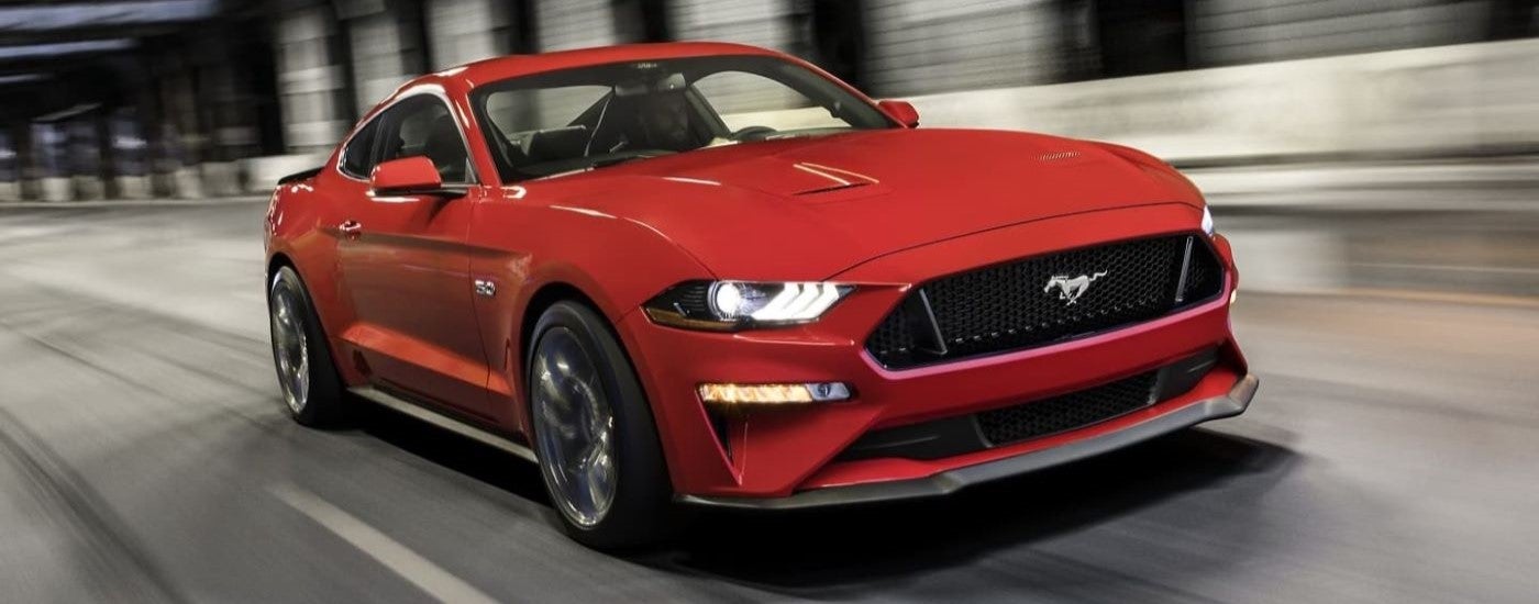 A red 2023 Ford Mustang GT driving down a road.