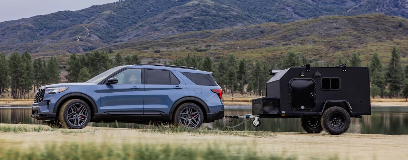 A blue 2025 Ford Explorer towing a trailer.