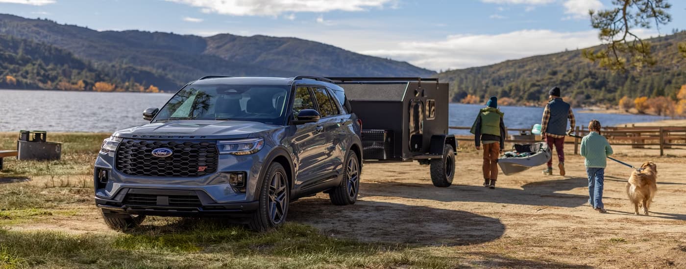 Grey 2026 Ford Explorer ST towing a trailer near a lake.