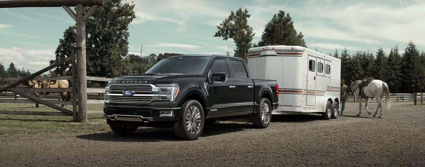 Black 2026 Ford F-150 towing a trailer near a ranch.