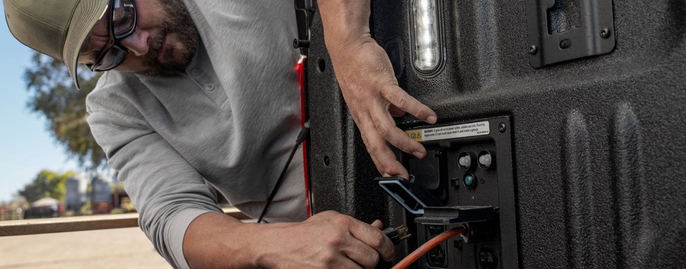 Person using the bed outlet on a 2025 Ford F-150