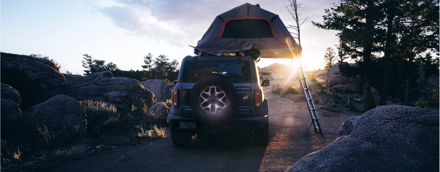 Grey 2026 Ford Bronco parked off-road with a rooftop tent from the rear