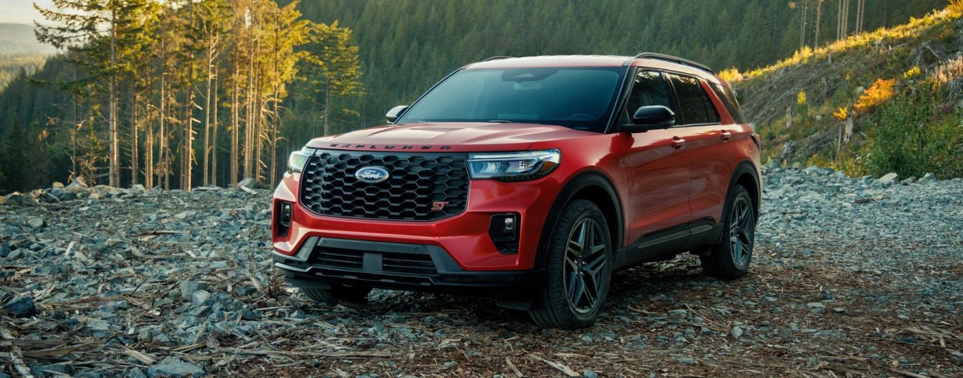 Red 2026 Ford Explorer ST parked on a rocky flat area in the woods.