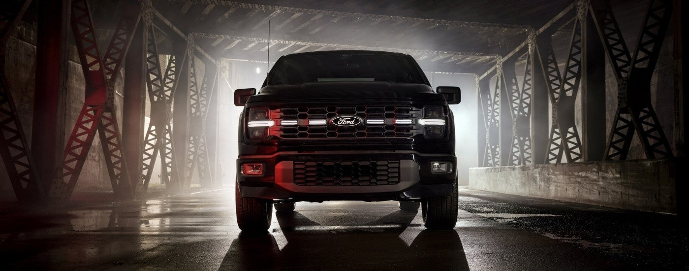 A black 2025 Ford F-150 Lobo under a bridge at night.