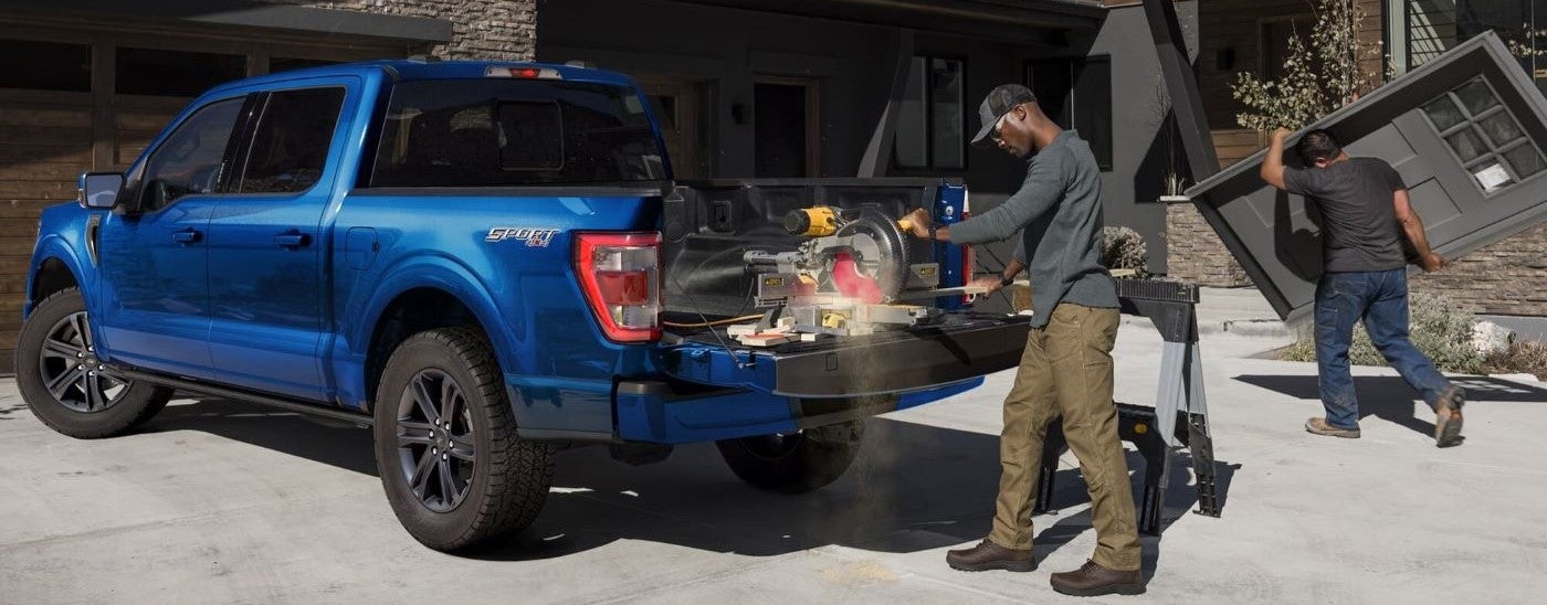 Person operating a work saw from the bed of a dark blue 2025 Ford F-150 Sport after visiting a dealer with a work trucks for sale in St. Clair.